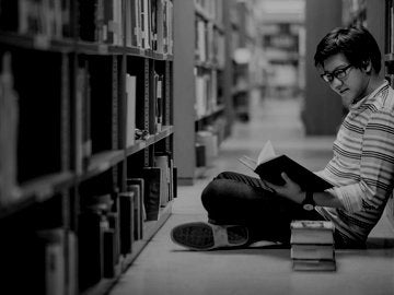 Young Asian man university student reading book in library