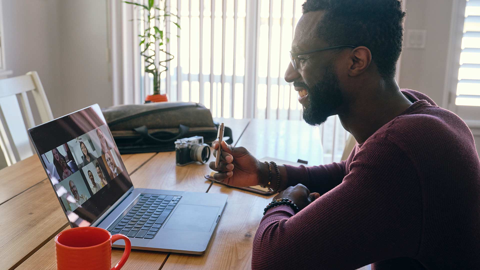 An African American man working at home, participating in a videoconference call on a computer