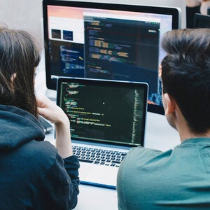 two programmers looking at computer screens together